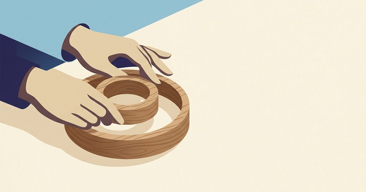 Two nested wooden rings on a desk, a smaller one resting inside a larger one