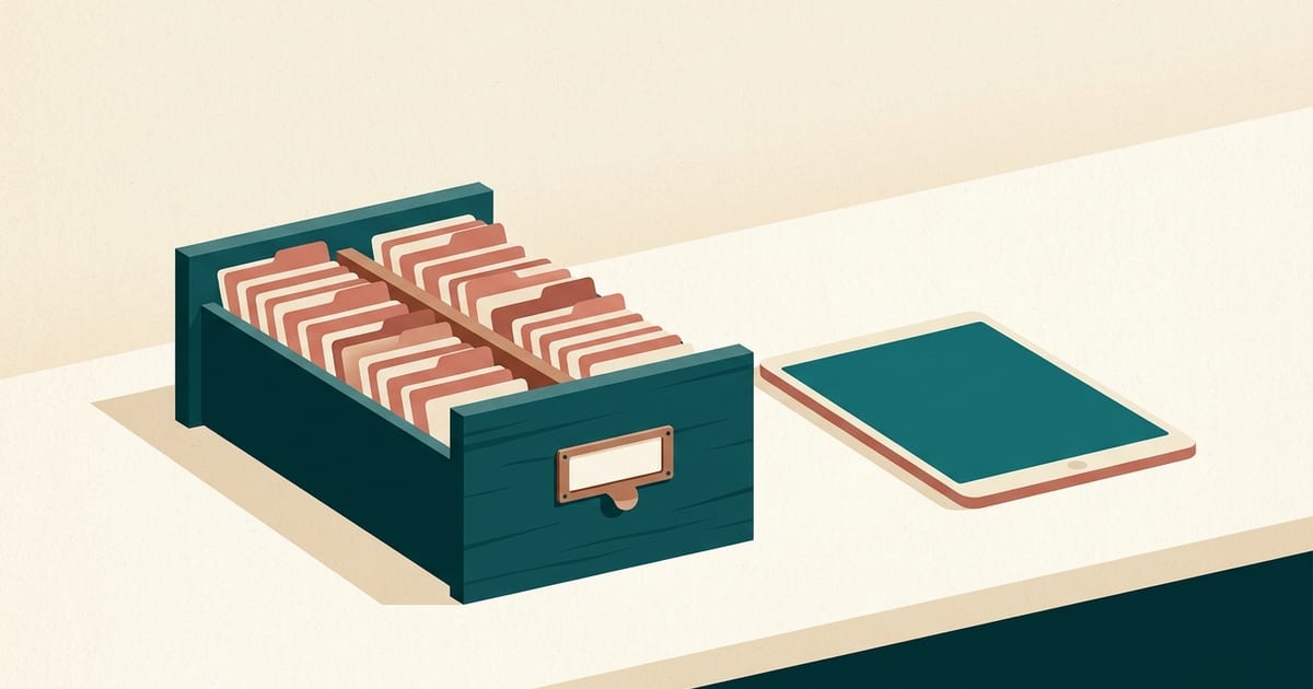 An open card-catalogue drawer beside a tablet on a counter